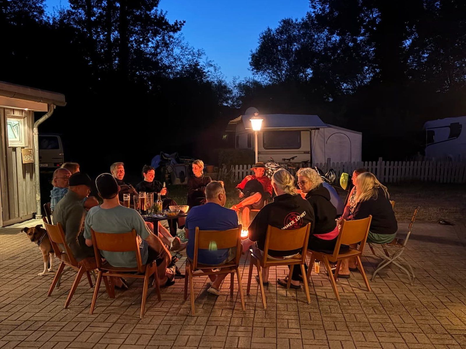 Abendliche Lagerfeuer-Runde mit Gästen und Team auf einem Campingplatz
